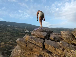 Murielle standing on a big rock, bent forward, in the background the sky.