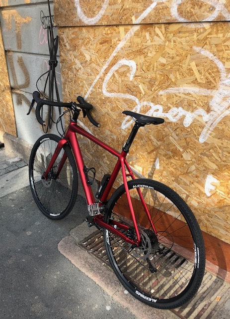 Rød racersykkel stående mot en vegg