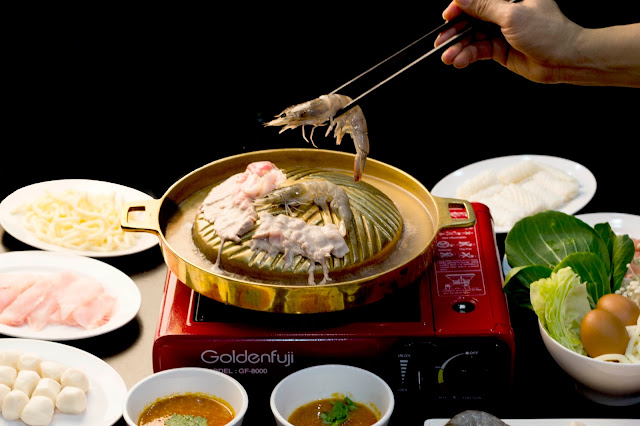 Photo of someone using chopstick to grab raw prawn