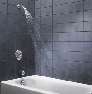 Stock photo of a shower with gray tile walls, spraying water into a white tub