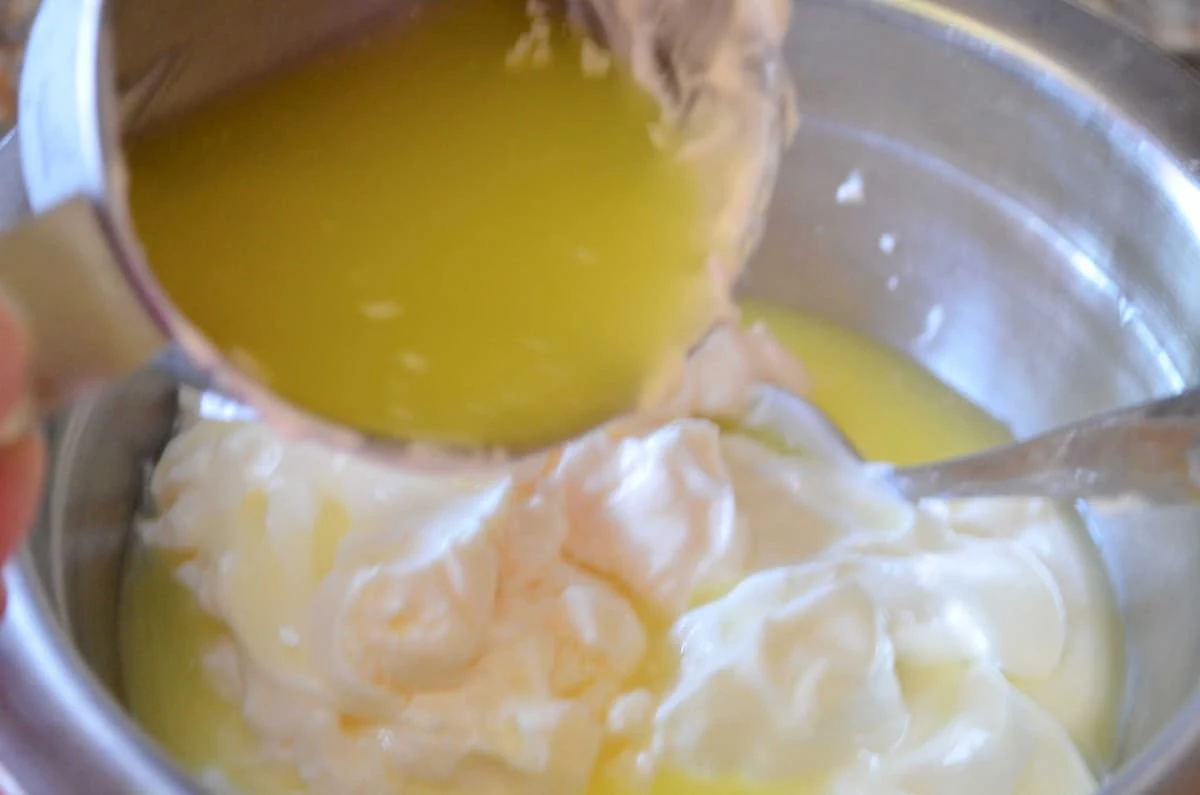 Dill Pickle juice being poured into dill dressing in a stainless steel bowl.