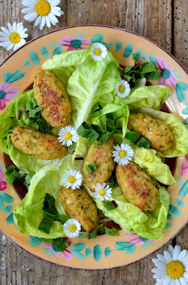 Knusprig gebräunte Karfiol-Nuggets liegen auf einem Bett aus Salatblättern und sind mit Gänseblümchen garniert.