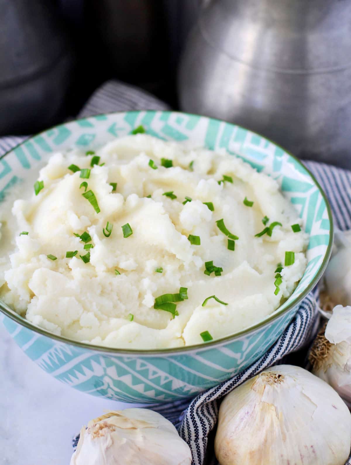 Creamy Garlic Mashed Potatoes with garlic heads next to the bowl.