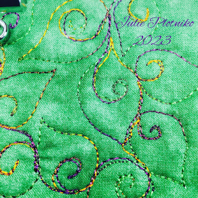 A stitched design of curly leaves on green fabric