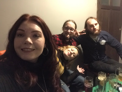 me and three friends grinning at the camera, with empty glasses on a green table next to us