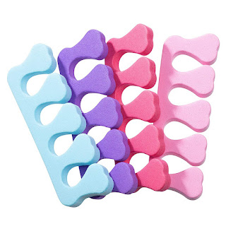 Four toe separators used for nail polish, each a different colour, lie fanned out on a white background.