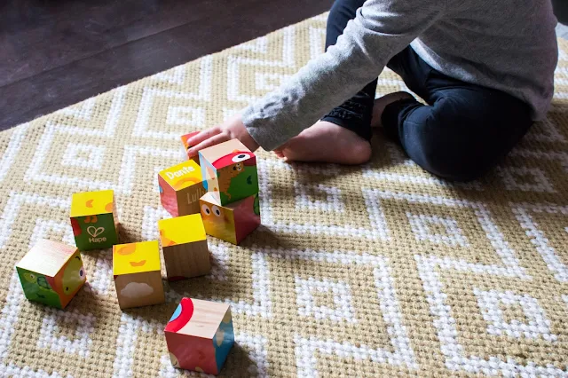 A little person playing with colourful blocks with pictures on