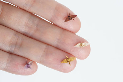Figuras de origami en miniatura sobre los dedos de una mano