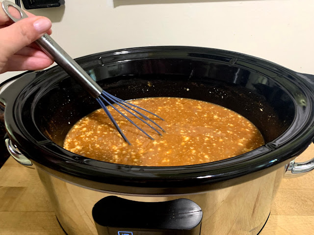 Whisking the cream cheese into the soup broth in the slow cooker.