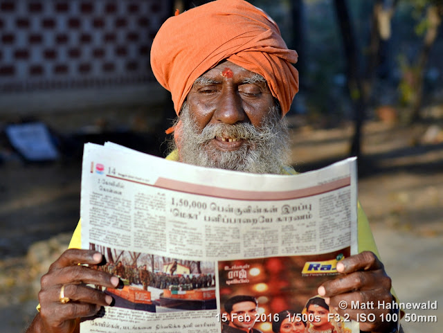 Matt Hahnewald Photography; Facing the World; closeup; street portrait; outdoor; candid; Asia; South Asia; India; Tamil Nadu; Tiruvannamalai; orange turban; Nikon D3100; Nikkor AF-S 50mm f/1.8G; travel; travel destination; Shaivite sadhu; old sadhu; Hindu; Hinduism; photography; colour; portraiture; person; people; eyes; face; religion; third eye; reading; studying; newspaper; Tamil language; morning light; focused; Hill of Arunachala; girivalam; giripradakshina; red tilaka mark