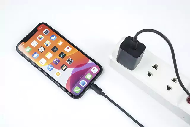 iPhone 13 on a table with a Lightning cable by its charging port