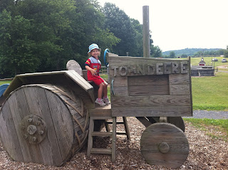 picture of child on play equipment made to look like John Deere tractor