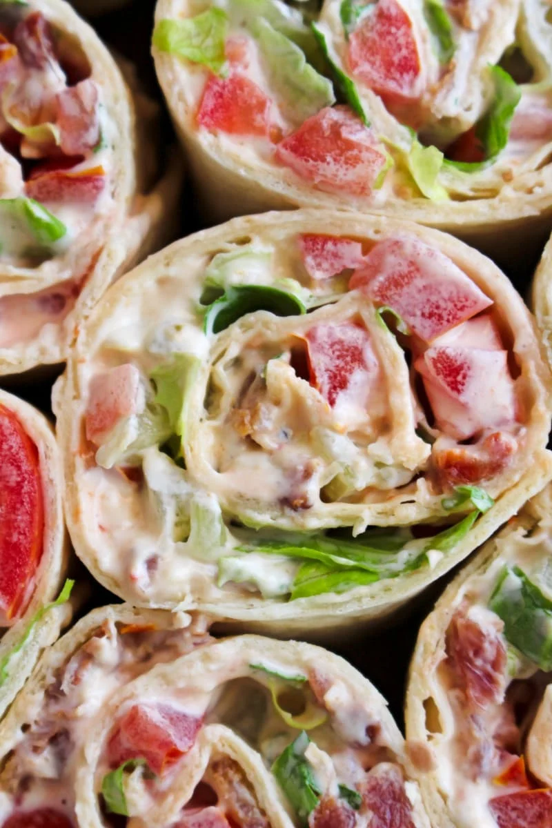 Closeup top view of Bacon, Lettuce, and Tomato Pinwheels on a cutting board.