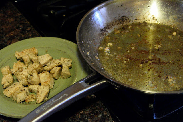 The cooked chicken on a plate beside the skillet on the stove. 