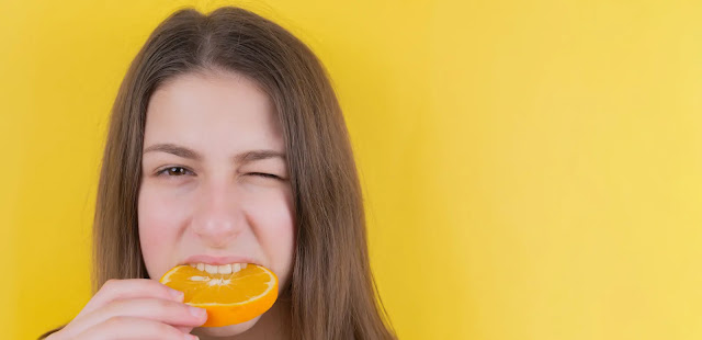 model eating a slice of orange