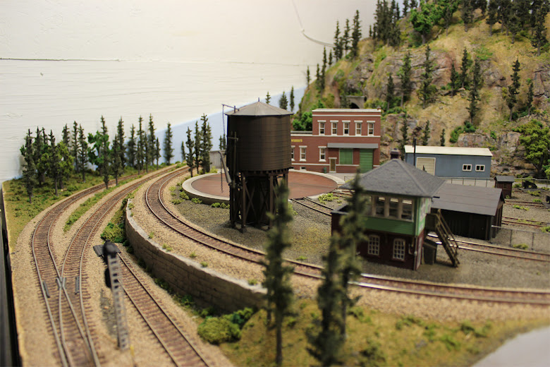 A railyard scene surrounded by several lines of railroad track and a plaster retaining wall