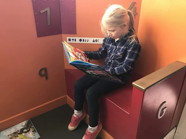 A girl sitting in a reading corner fully absorbed in a book