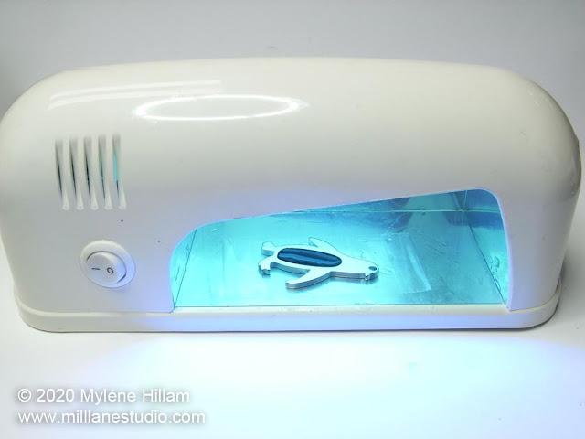 The penguin keychain being cured in a UV nail lamp