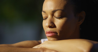 Black woman sitting with eyes closed outdoors