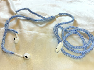 Earbuds with cord covered in light blue yarn