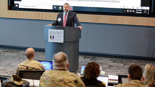 Dr. David Tribble stands at a podium delivering remarks to a crowd.