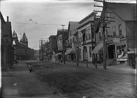 A black and white photograph of a mostly empty street.