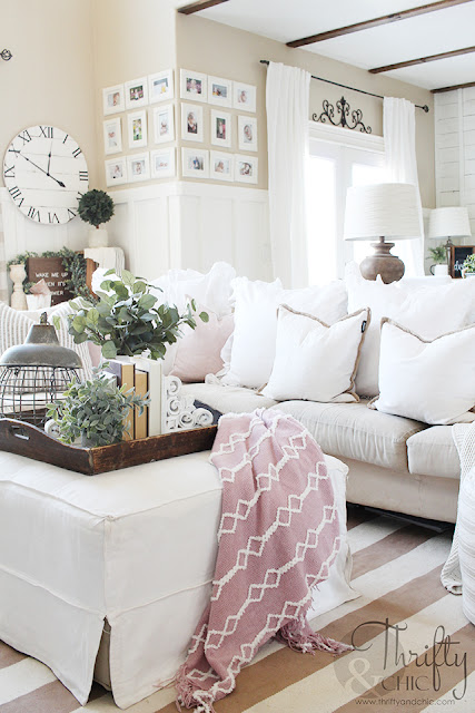 living room with white couch, ottoman, striped rug and pink blanket