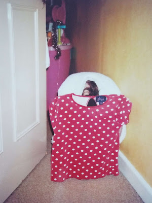 Ellie when she was young, trying to create a lookbook with her polka dot top, trying not very well to hide behind a towel to make white background, with her head poking out.