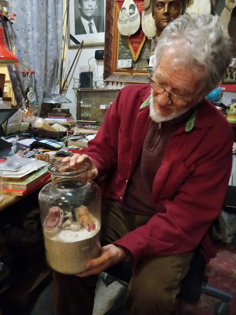 picture of man holding a glass jar next to a table