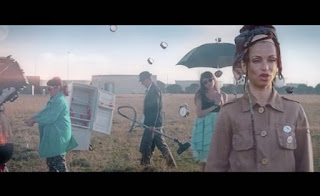 Fotograma videoclip donde aparece cantante Siska y personajes de fondo