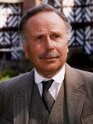 Edward Hardwick as Dr Watson smiles and looks to the right