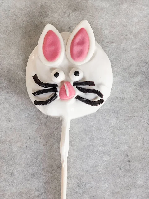 Bunny Lofthouse Frosted Sugar Cookie Pops, frosted sugar cookies, and cream cheese come together to make the most amazing delicious no-bake pops.  Start with flattening the cookie pop, dip in melted candy melts and decorate with an Easter Bunny decorating kit.  A quick and easy Easter dessert just got a little sweeter.