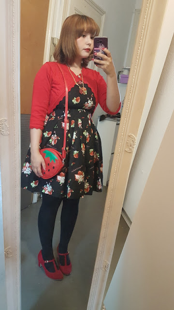 mirror selfie of auris in a black strawberry dress and a red strawberry bag