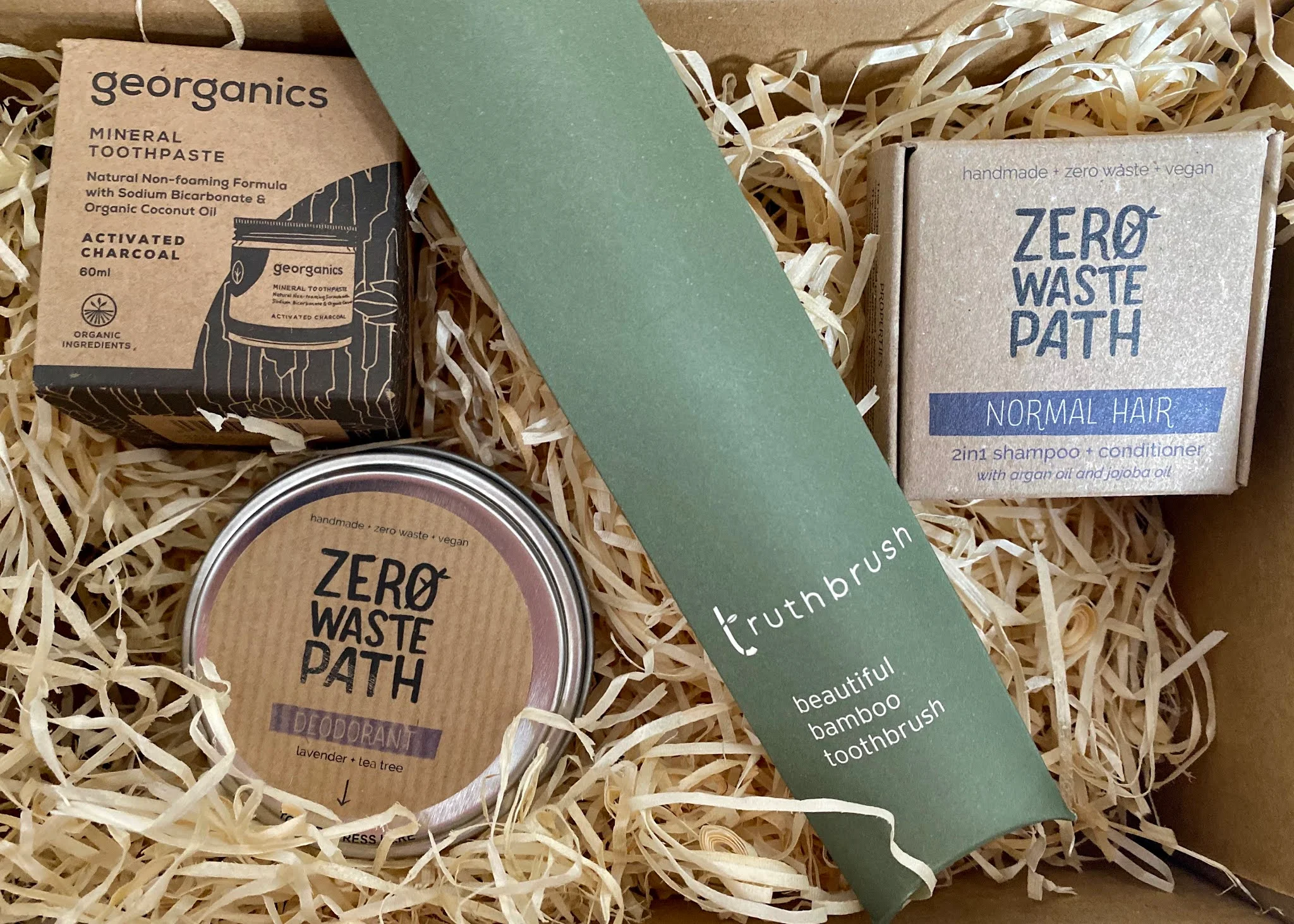 A delivery of eco products for the bathroom: a deodorant tin, jar of toothpaste, bamboo toothbrush and shampoo bar. All in their packaging