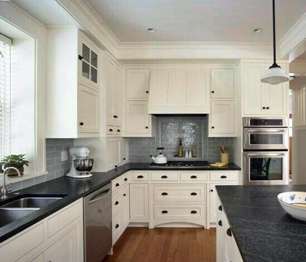 white cabinets with black countertops and gray subway tile backsplash