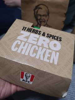 A large grey rectangular box with 11 herbs and spices in black font with zero chicken in white font on a bright background