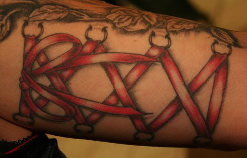 Tattoo of Corset Piercings Laced with Red Ribbon on Arm