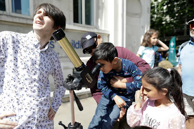 Astronomy PhD student letting children play with his telescope