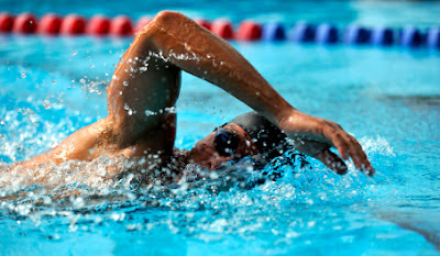 picture of a relaxed man swimming freestyle his lane in the pool.