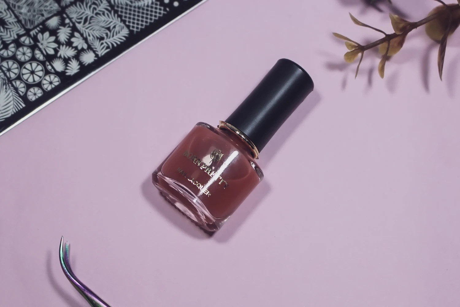 close-up of a nail polish bottle with a strawberry nail polish on a pink background