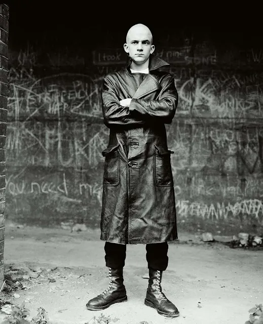 Bald man and a black and white photograph wearing a black leather trench coat