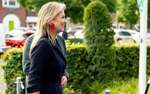 Queen Maxima wore a navy blue wrap front jumpsuit by Natan Couture. She wore red suede pumps