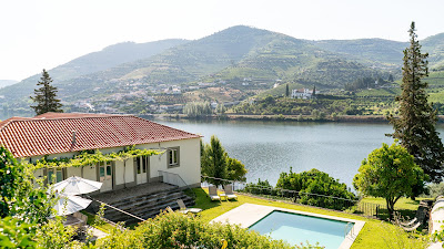 uma casa com piscina à margens do rio Douro e o vale de vinhas na outra margem