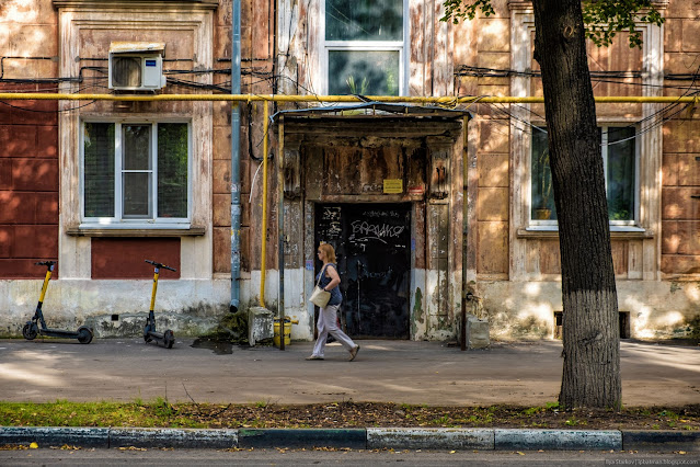 Женщина идет вдоль пошарпанного здания