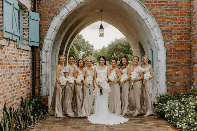 bride with bridesmaids in champagne dresses standing in front of casa feliz