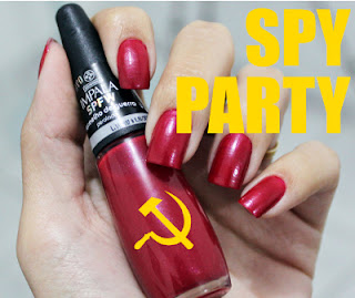 A hand with red nails holds a bottle of nail polish bearing a hammer and sickle, with the text SPY PARTY