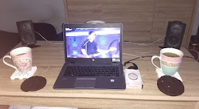 Salontafel met koppen thee, koeken, boxen en laptop met Kensington in beeld