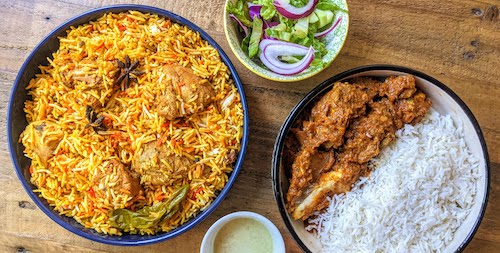 A plate of chicken biryani and another one with goat karahi shown together