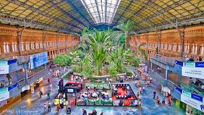 Madrid Atocha (Spanish: Estación de Madrid Atocha, also named Madrid Puerta de Atocha) is the largest railway station in Madrid. It is the primary station serving commuter trains (Cercanías), intercity and regional trains from the south, and the AVE high speed trains from Barcelona (Catalonia), Saragosse (Aragon), Seville (Andalusia) and Valencia (Levante Region). These train services are run by the Spanish national rail company, Renfe. The station is in the Atocha neighborhood of the district of Arganzuela. The original façade faces the Plaza del Emperador Carlos V, a site at which a variety of streets converge, including the Calle de Atocha, Paseo del Prado, Paseo de la Infanta Isabel, Avenida de la Ciudad de Barcelona, Calle de Méndez Álvaro, Paseo de las Delicias, Paseo de Santa María de la Cabeza, and Ronda de Atocha.