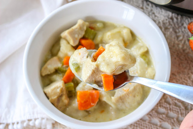 a spoonful of chicken and dumplings over a white bowl.